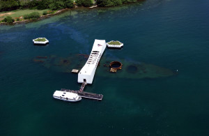 An aerial view of the USS Arizona Memorial with a US Navy (USN) Tour Boat, USS Arizona Memorial Detachment, moored at the pier as visitor disembark to visit and pay their respects to the Sailors and Marines who lost their lives during the attack on Pearl Harbor on December 7, 1941.